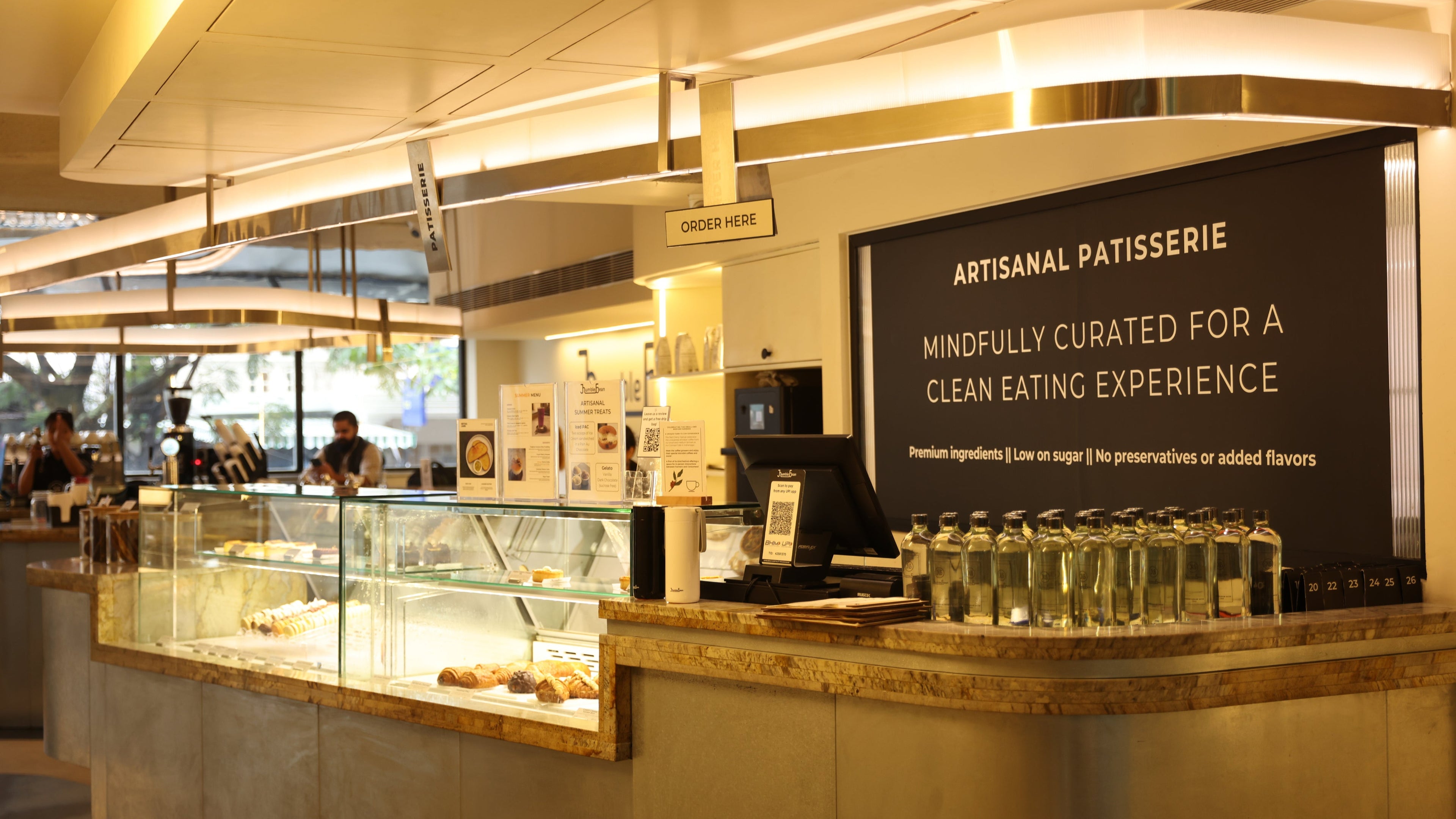 Interior of a bakery with a counter and display cases, featuring a sign for 'Artisanal Patisserie'.